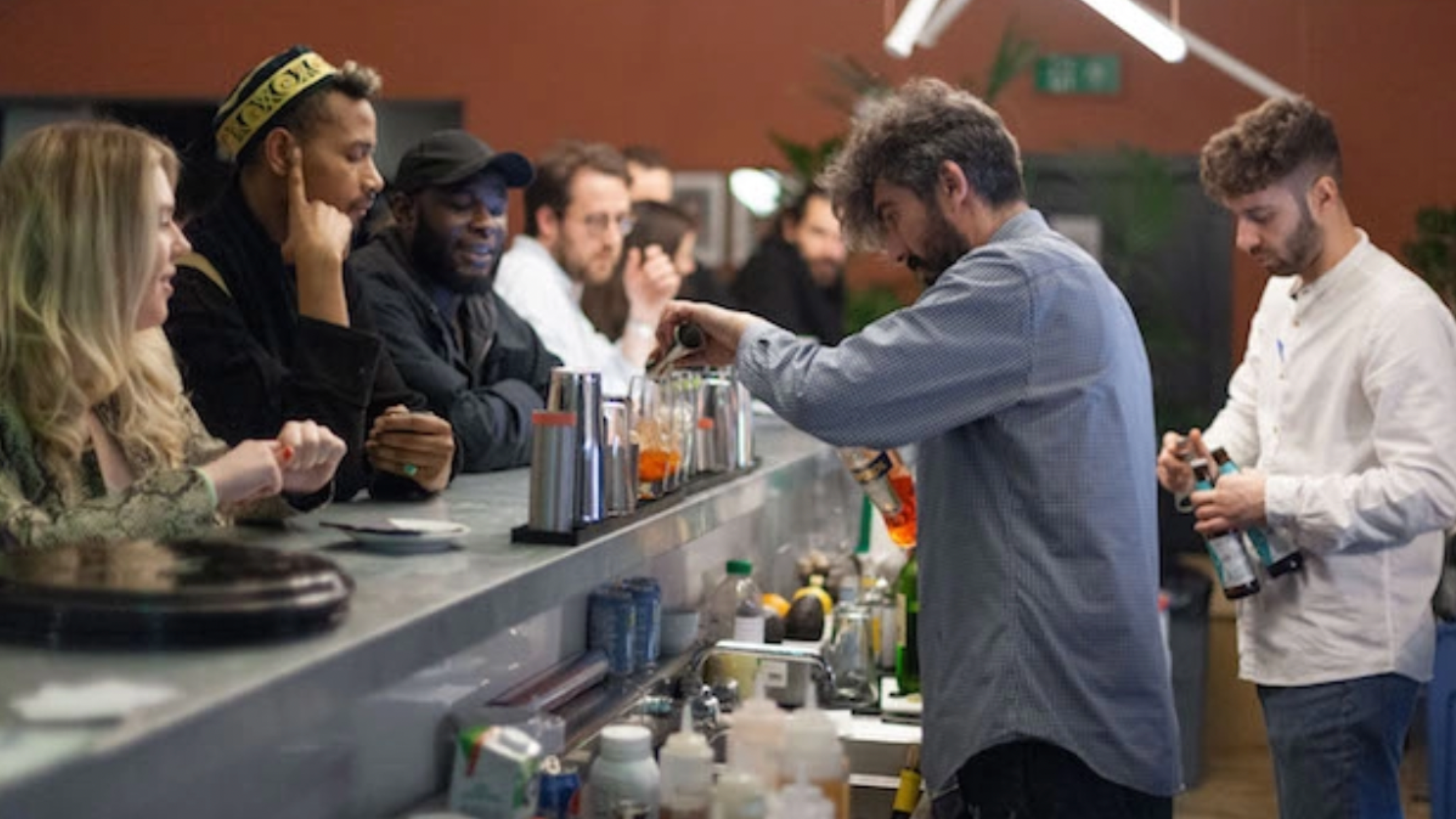A photo of two barmen serving a mixed group of punters at EartH Kitchen in Dalston
